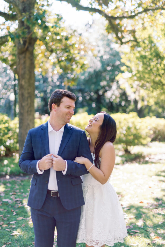 Couple laughing together beneath the oak trees during a Forsyth Park engagement session