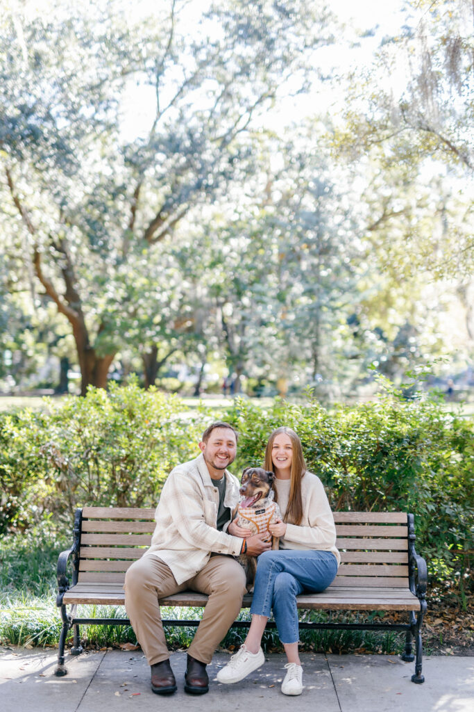 Couple sitting on a park bench with their dog during a Savannah engagement session