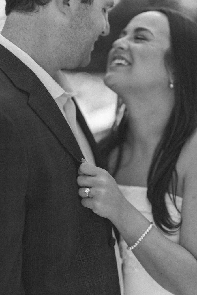 Black-and-white close-up of an engaged couple laughing and kissing
